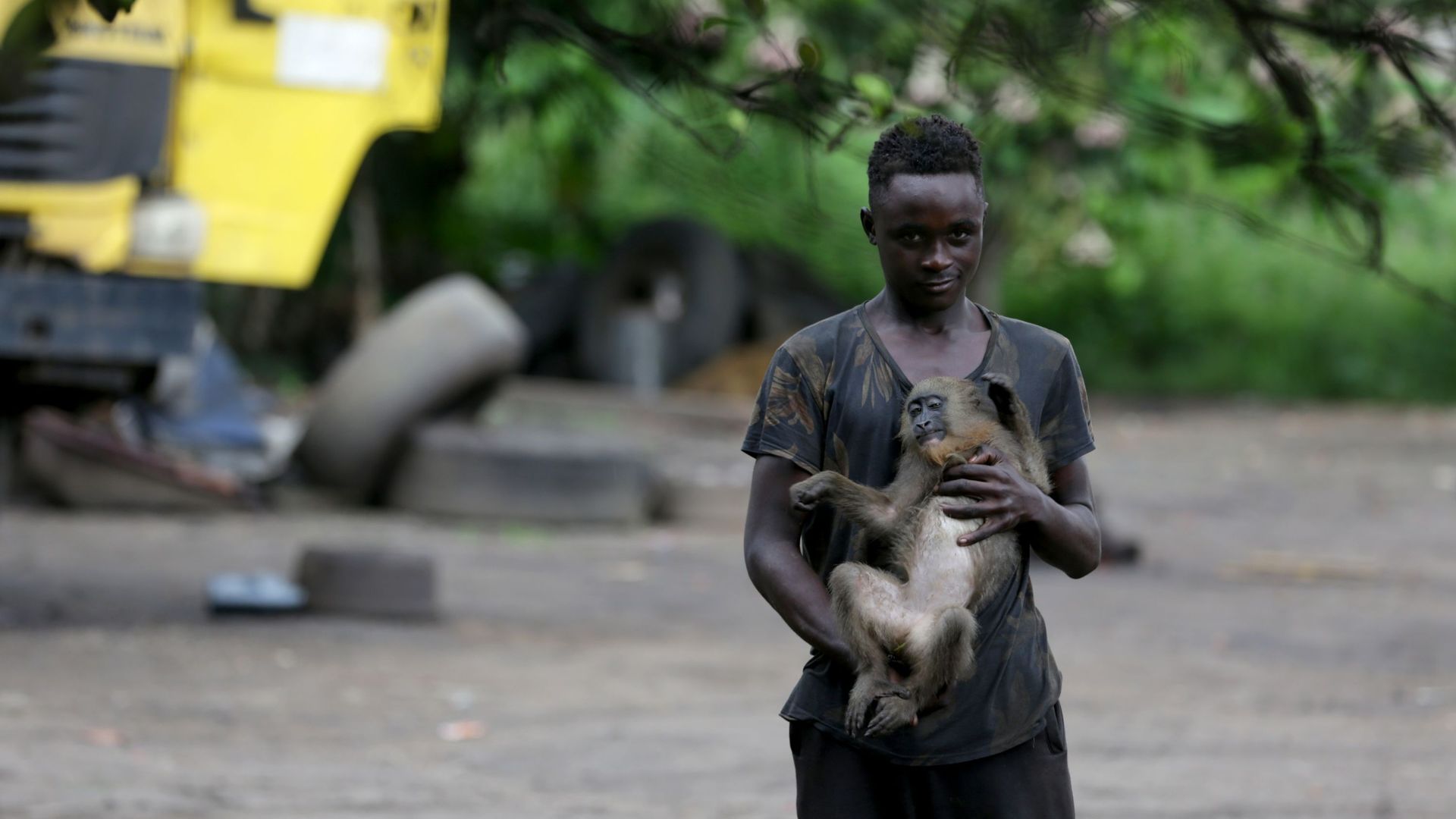 Un jeune Guinéen joue avec un singe sauvage à Franceville. Janvier 2021.