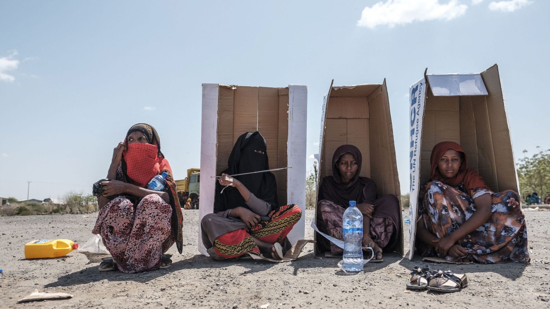 Des femmes sont assises sous des boîtes en carton branchées du Haut-Commissariat des Nations Unies pour les réfugiés (HCR) alors qu’elles attendent d’être enregistrées par les autorités dans l’enceinte de l’hôtel Agda, dans la ville de Semera, dans la rég