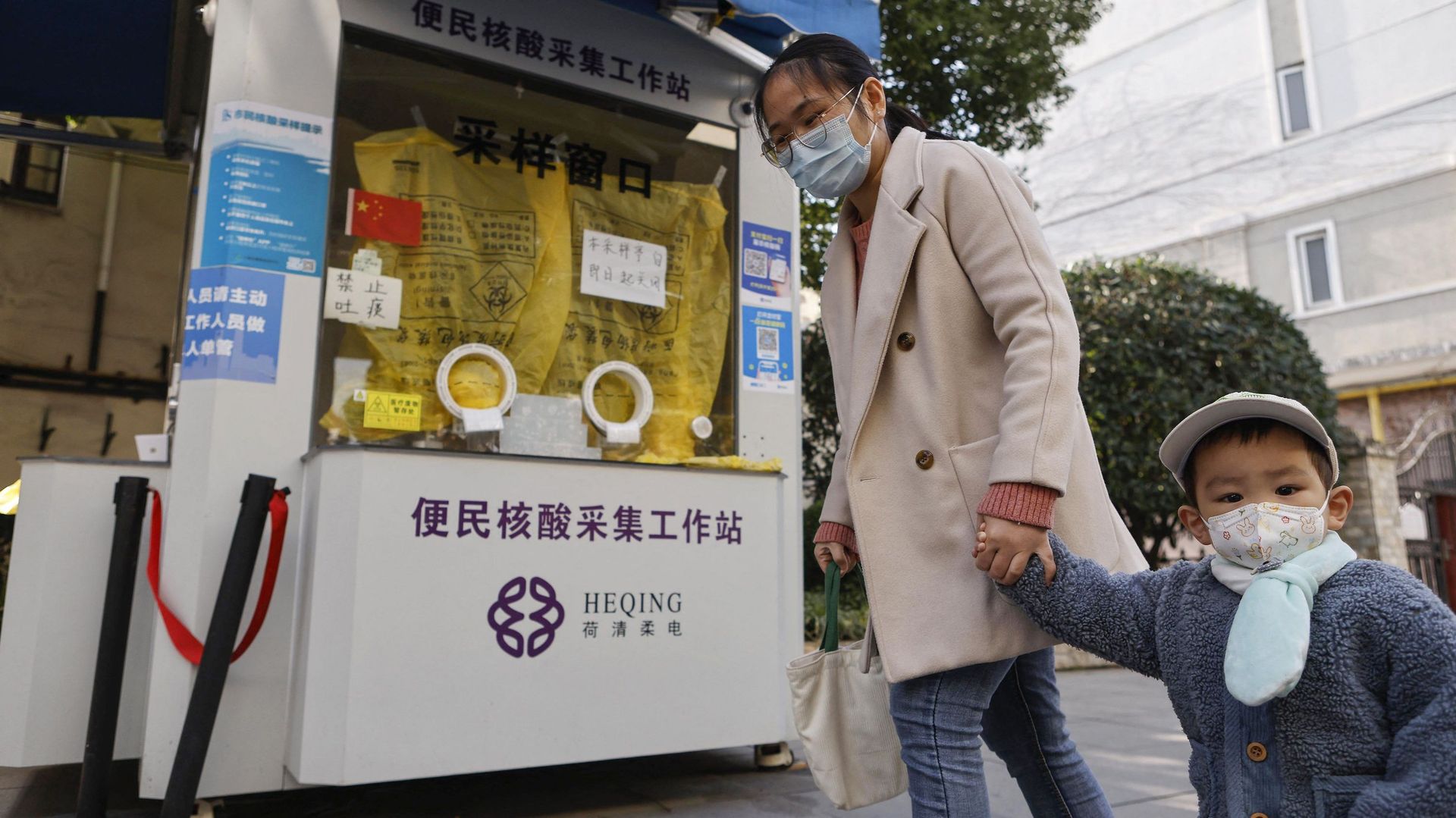 Cette photo prise le 13 décembre 2022 montre une femme et un enfant passant devant un stand de test fermé de Covid à Shanghai.
