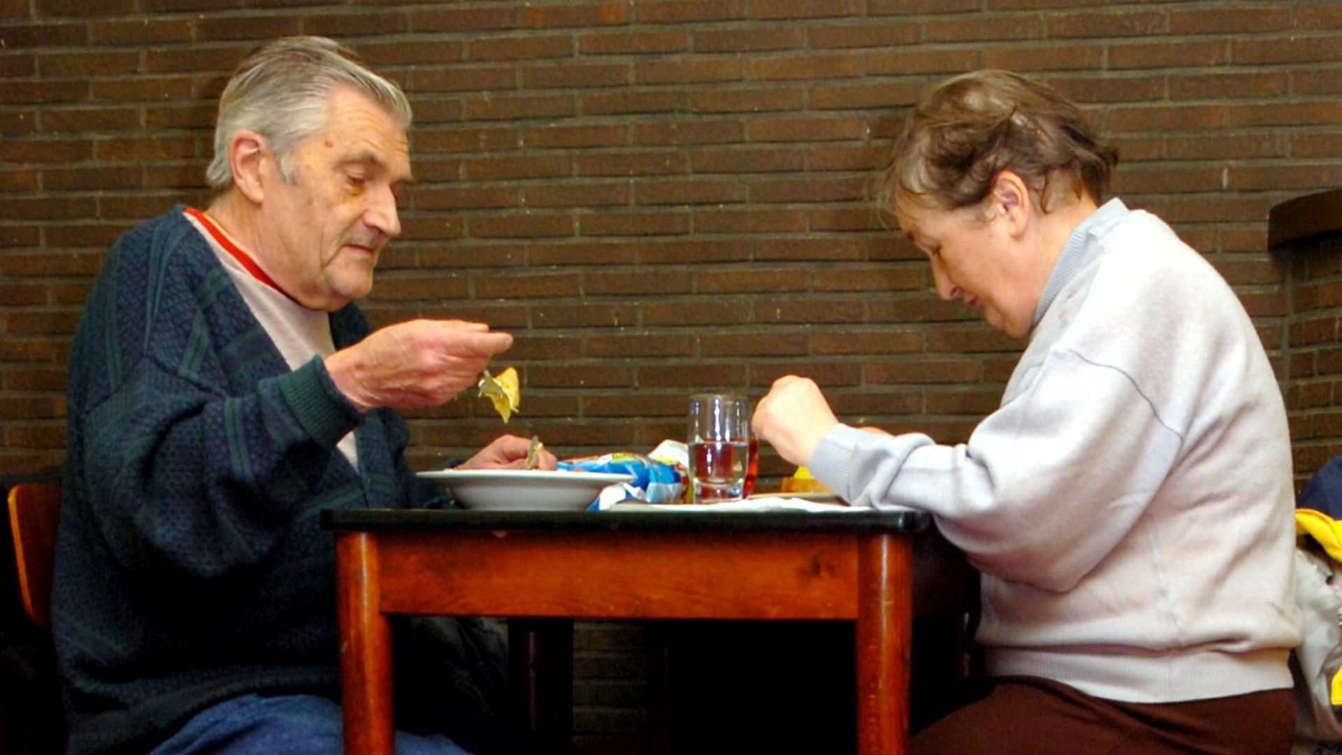 Deux personnes profitent d'un repas chaud offert par "Les petits riens" en décembre 2005.