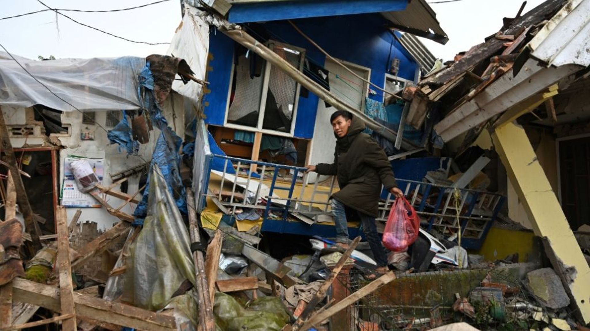 Un homme récupère des affaires dans une maison détruite après un tremblement de terre de magnitude 5,6 qui a fait au moins 162 morts, des centaines de blessés et des disparus à Cianjur, le 22 novembre 2022
