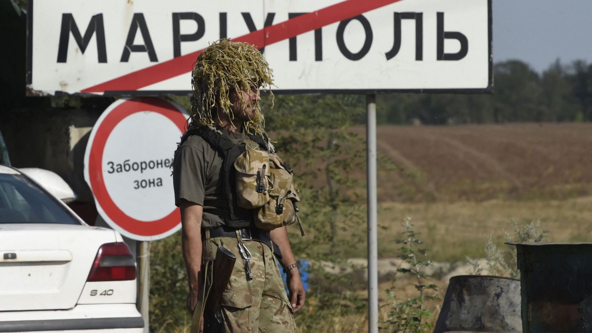 Un soldat de l'armée ukrainienne passe devant un panneau routier de la ville indiquant Marioupol 