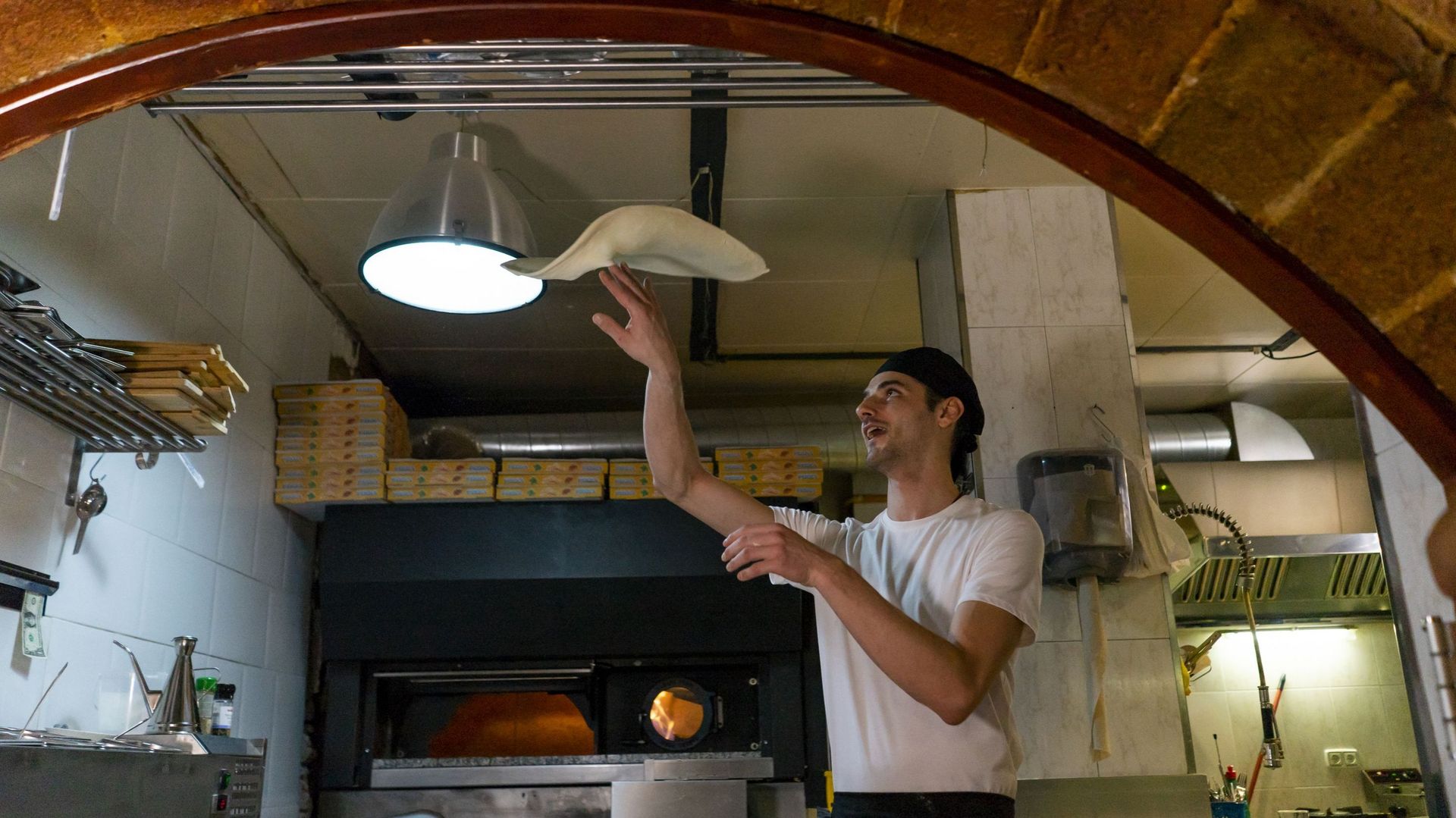 Pizza baker preparing pizza in kitchen throwing dough in the air