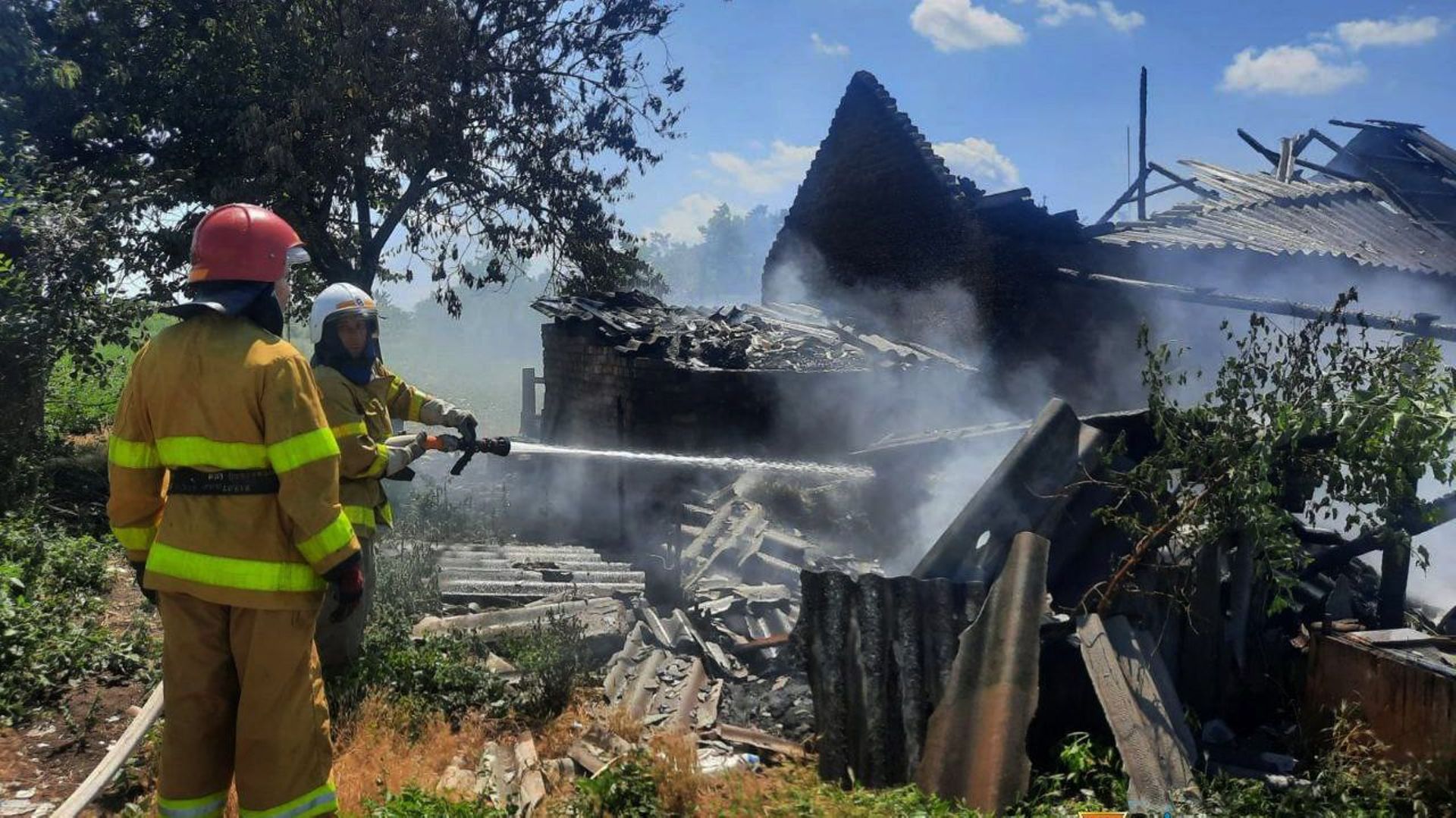 Cette photo distribuée par le service d’urgence ukrainien le 20 juillet 2022 montre des pompiers en train d’arroser une maison après un bombardement dans la région de Mykolaiv.