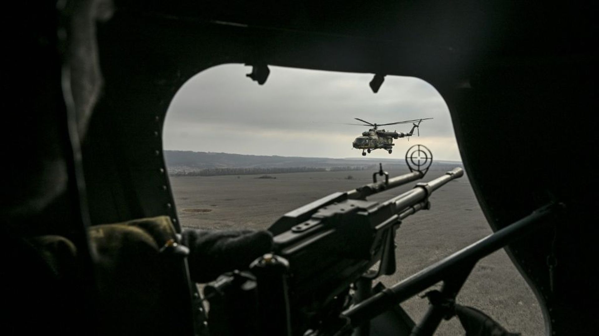 Un mitrailleur de sabord ukrainien dans un hélicoptère Mil MI-8 regarde un appareil du même modèle, le 10 mars 2023 au-dessus de l’est de l’Ukraine