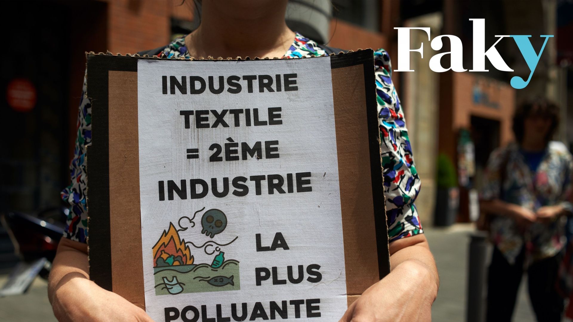 Une femme tient une pancarte sur laquelle on peut lire "Industrie textile = 2ème industrie la plus polluante". Des membres de XR Toulouse (Extinction Rebellion) ont organisé une manifestation devant un magasin pop-up SHEIN. Toulouse. France. 28 mai 2022.