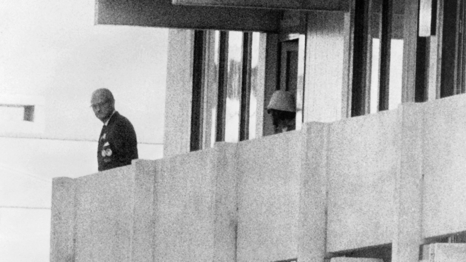 Un membre du commando palestinien apparaît sur le balcon de la délégation israélienne sous les yeux d’un officiel, le 5 septembre 1972, au village olympique de Munich.