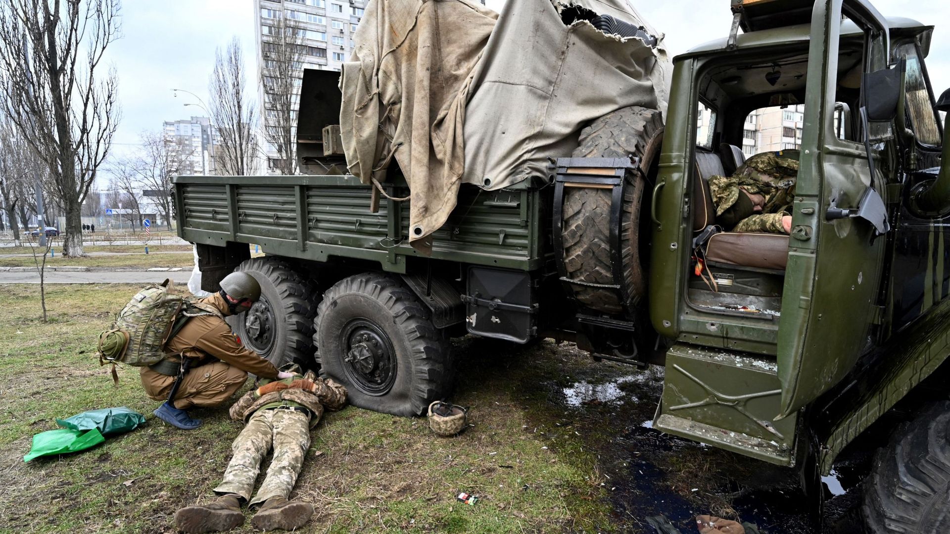 Un médecin militaire ukrainien (à gauche) examine le corps d'un militaire russe portant un uniforme de service ukrainien à côté d'un véhicule après que lui et les membres d'un groupe d'assaut aient été abattus lors d'une escarmouche dans la capitale ukrai