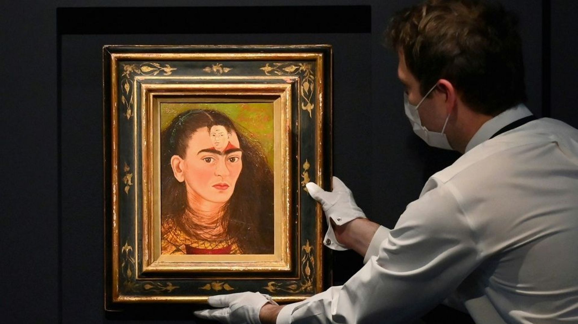 Un employé de Sotheby’s ajuste un autoportrait de Frida Kahlo, "Diego y yo", le 5 novembre 2021, à New York