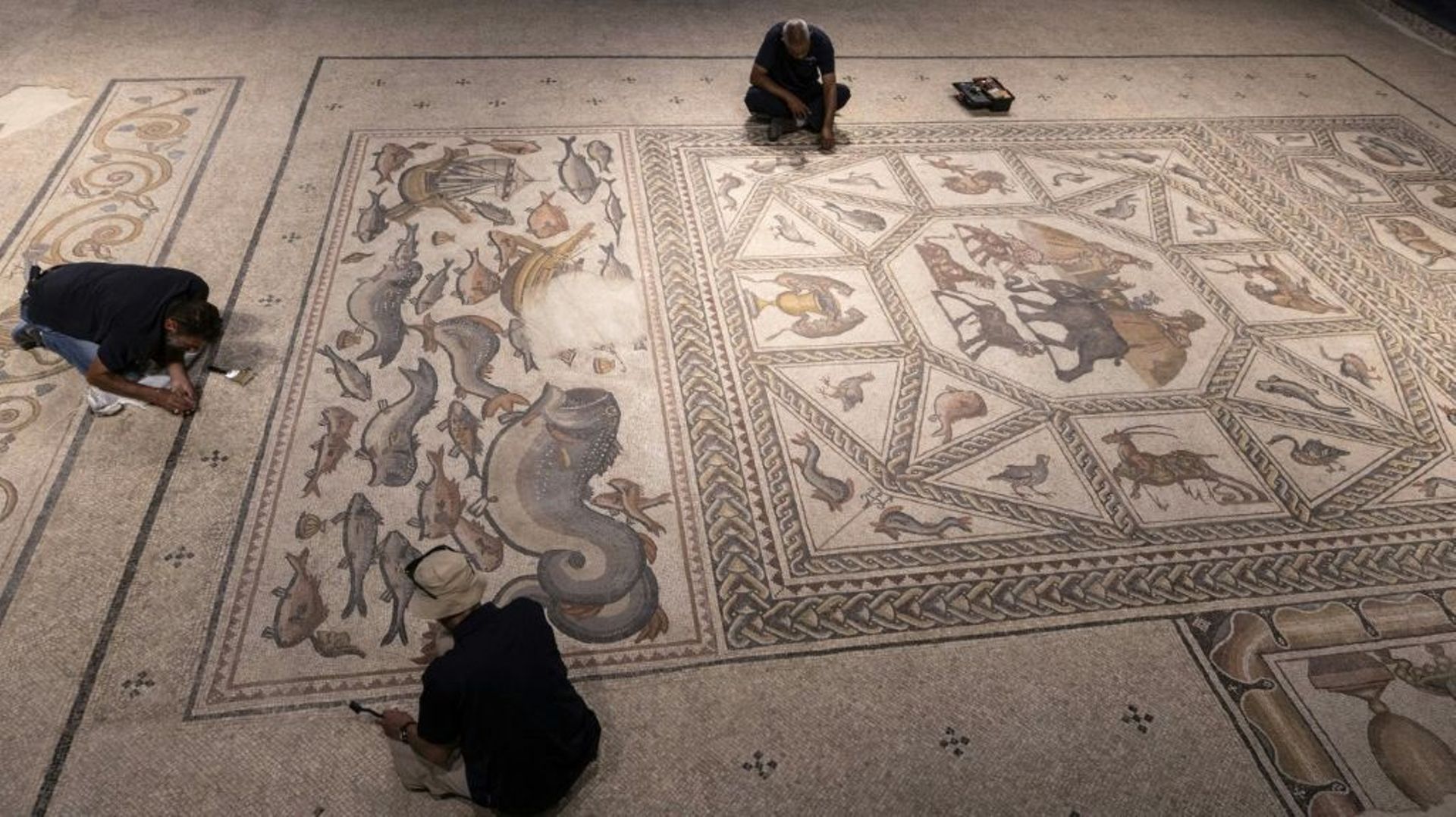 Des employés du musée archéologique travaillent sur la mosaïque de Lod, vieille d’environ 1700 ans, le 27 juin 2022 à Lod, dans le centre d’Israël
