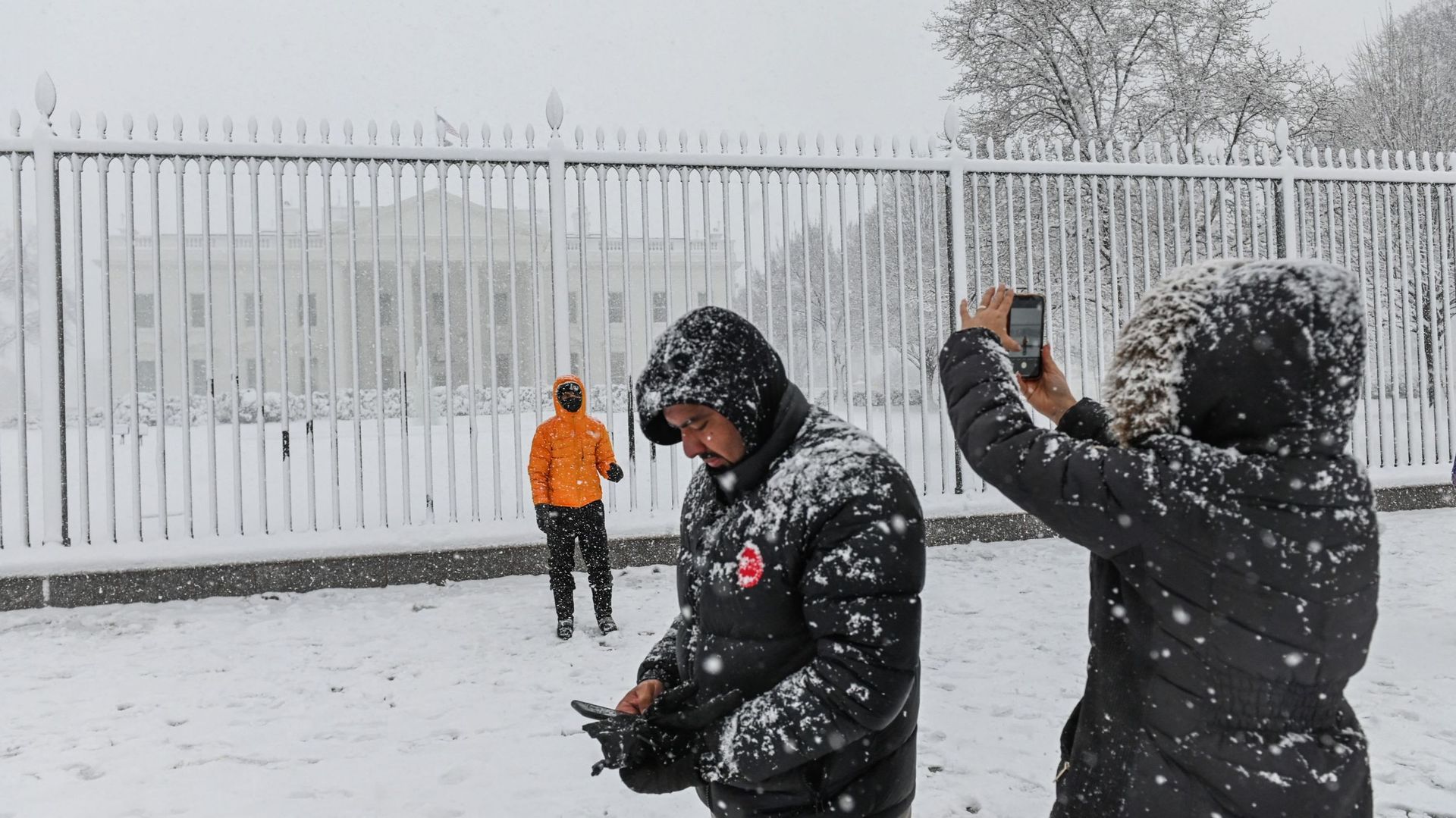 Une homme se fait prendre en photo par une femme alors qu'une tempête de neige s'abat sur la Maison Blanche, à Washington.