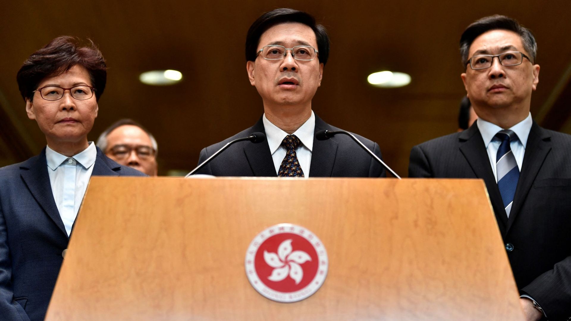 La cheffe de l’exécutif de Hong Kong Carrie Lam (à gauche) et le chef de la police Stephen Lo (à droite) regardent le chef de la sécurité de Hong Kong, John Lee (centre) s’adresser aux médias lors d’une conférence de presse à Hong Kong le 22 juillet 2019.