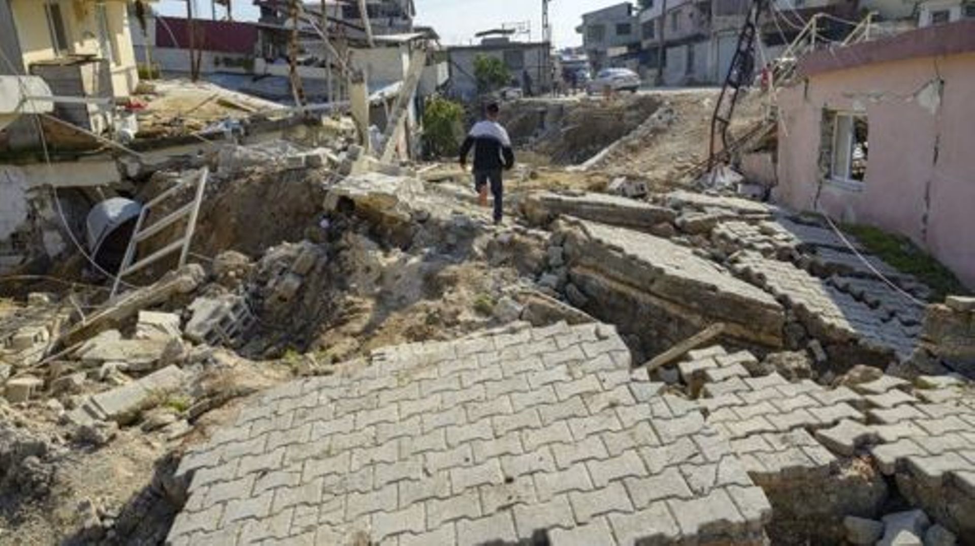 A youth runs across the upturned cobbled stoned street in Demirkopru, a small Turkish village now divided by a large crack in Hatay on February 18, 2023 . A 7.8-magnitude earthquake hit near Gaziantep, Turkey, in the early hours of February 6, followed by