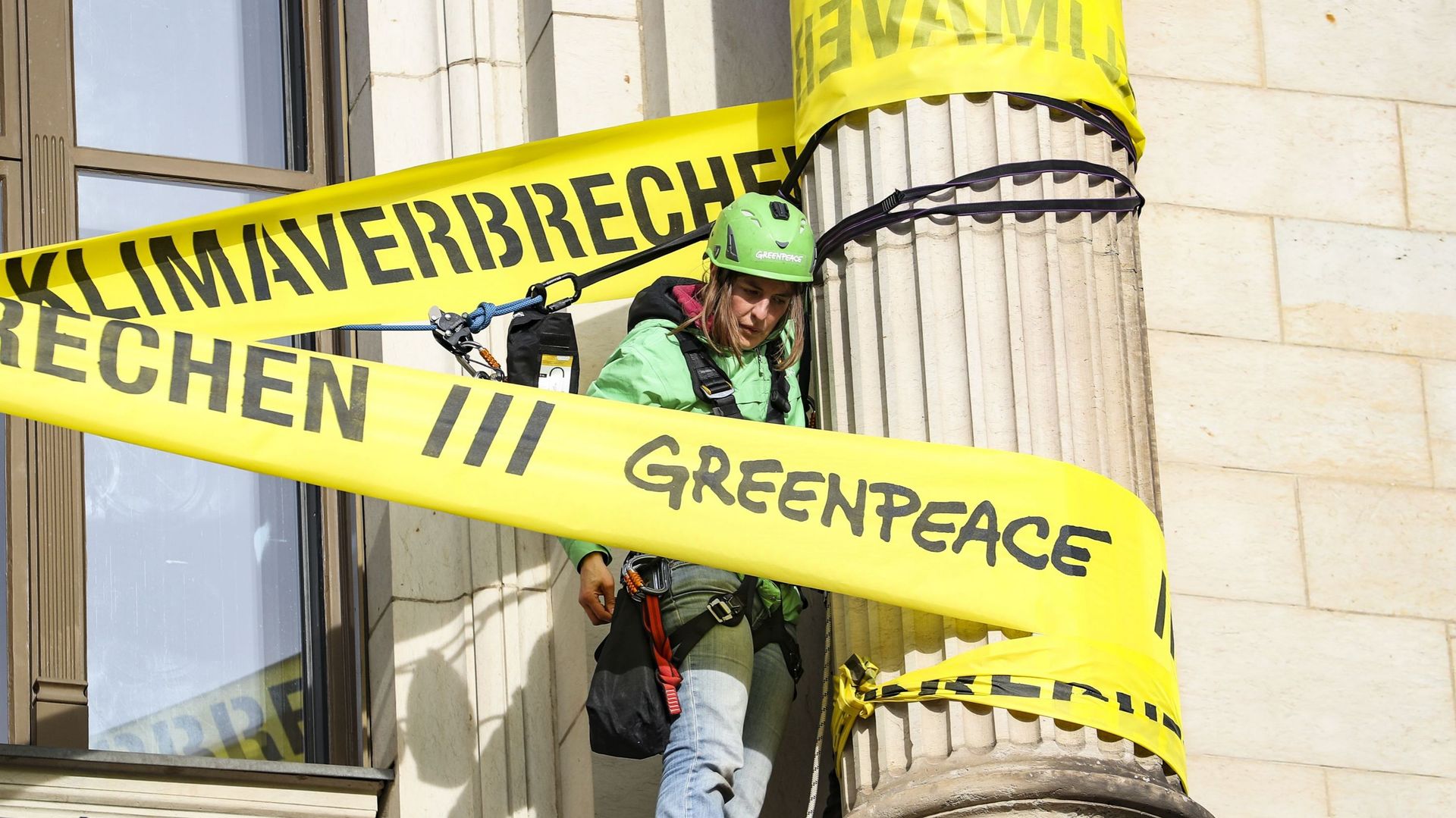 Des activistes de Greenpeace attachent un ruban de scène de crime autour des colonnes du bâtiment qui abrite le ministère fédéral des transports en lisant "crime climatique", lors de la manifestation contre les politiques environnementales et climatiques 
