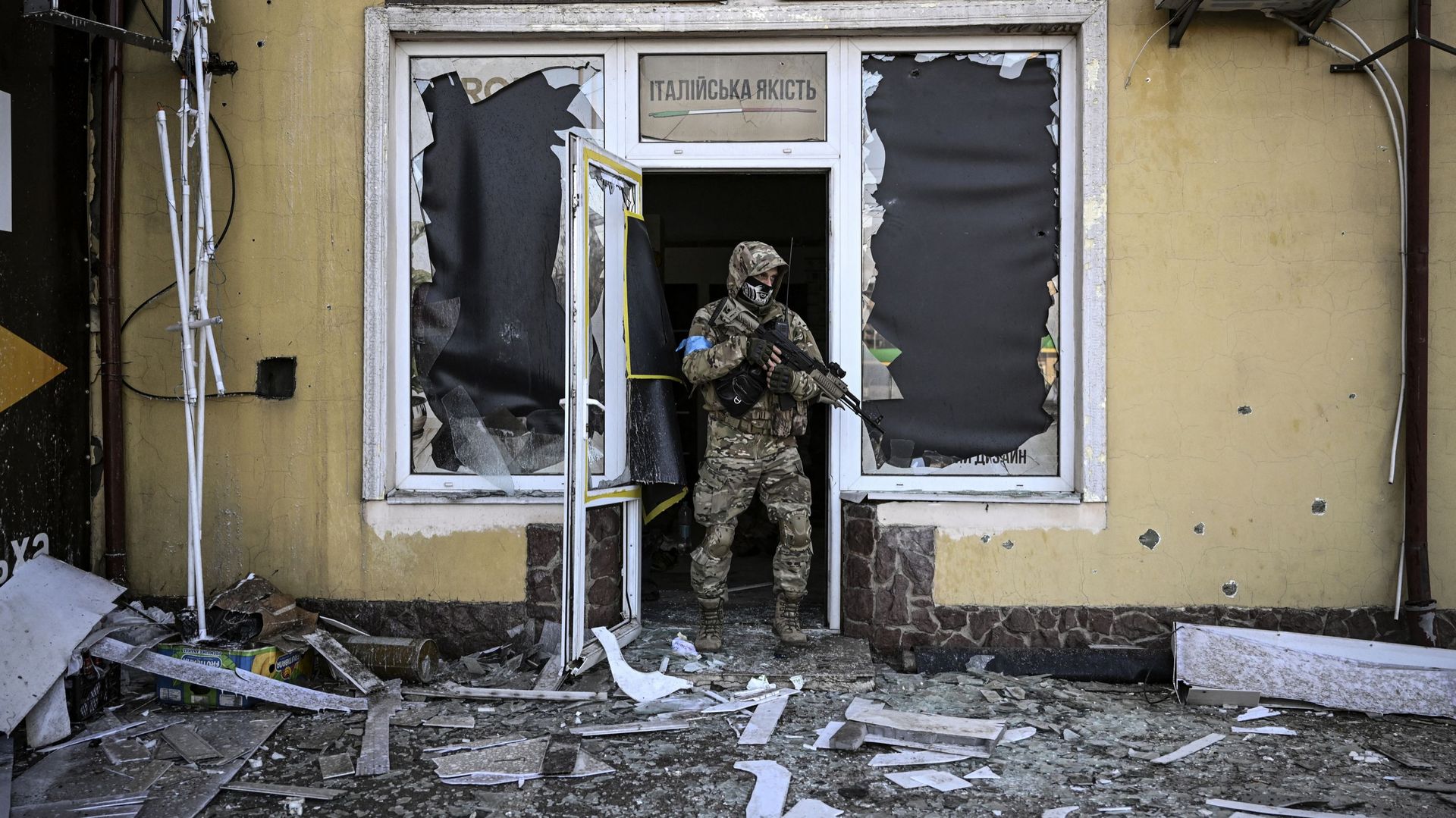 Un militaire ukrainien sort d'un bâtiment endommagé après un bombardement à Kiev, le 12 mars 2022. Les forces russes sont positionnées autour de Kiev, le 12 mars 2022, et "bloquent" Marioupol, où des milliers de personnes subissent un siège dévastateur, d
