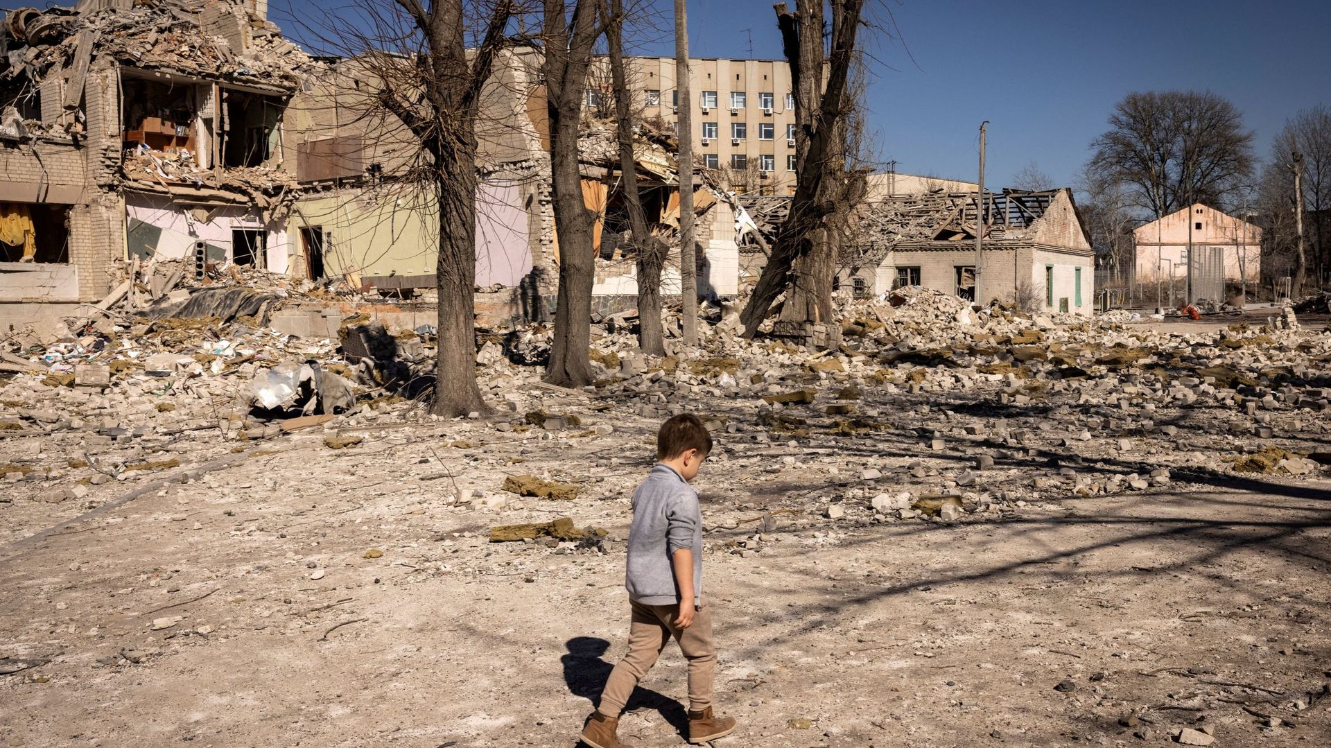 Un enfant marche devant une école endommagée dans la ville de Zhytomyr, dans le nord de l'Ukraine, le 23 mars 2022.