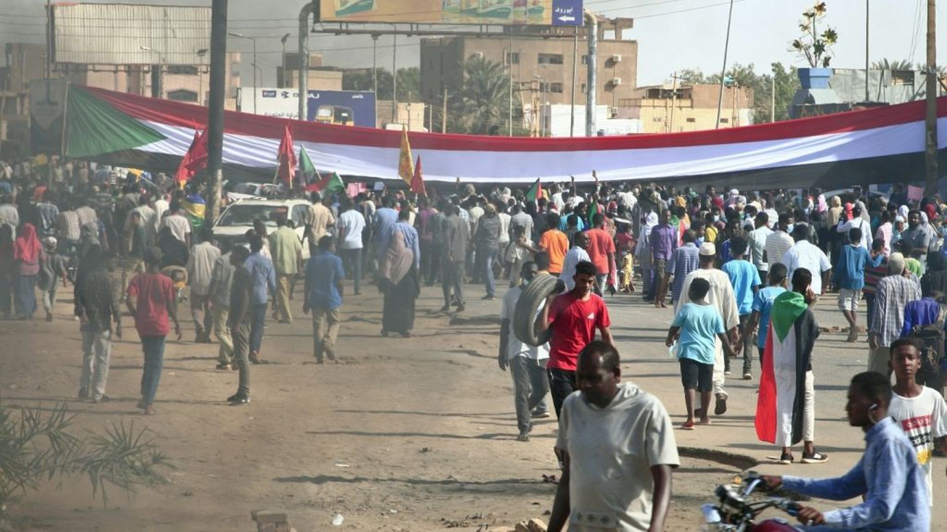 Des manifestants ont dressé un gigantesque drapeau soudanais lors d’une manifestation à Omdourman, la ville jumelle de Khartoum, pour réclamer le retour du pouvoir civil au Soudan, le 13 décembre 2021