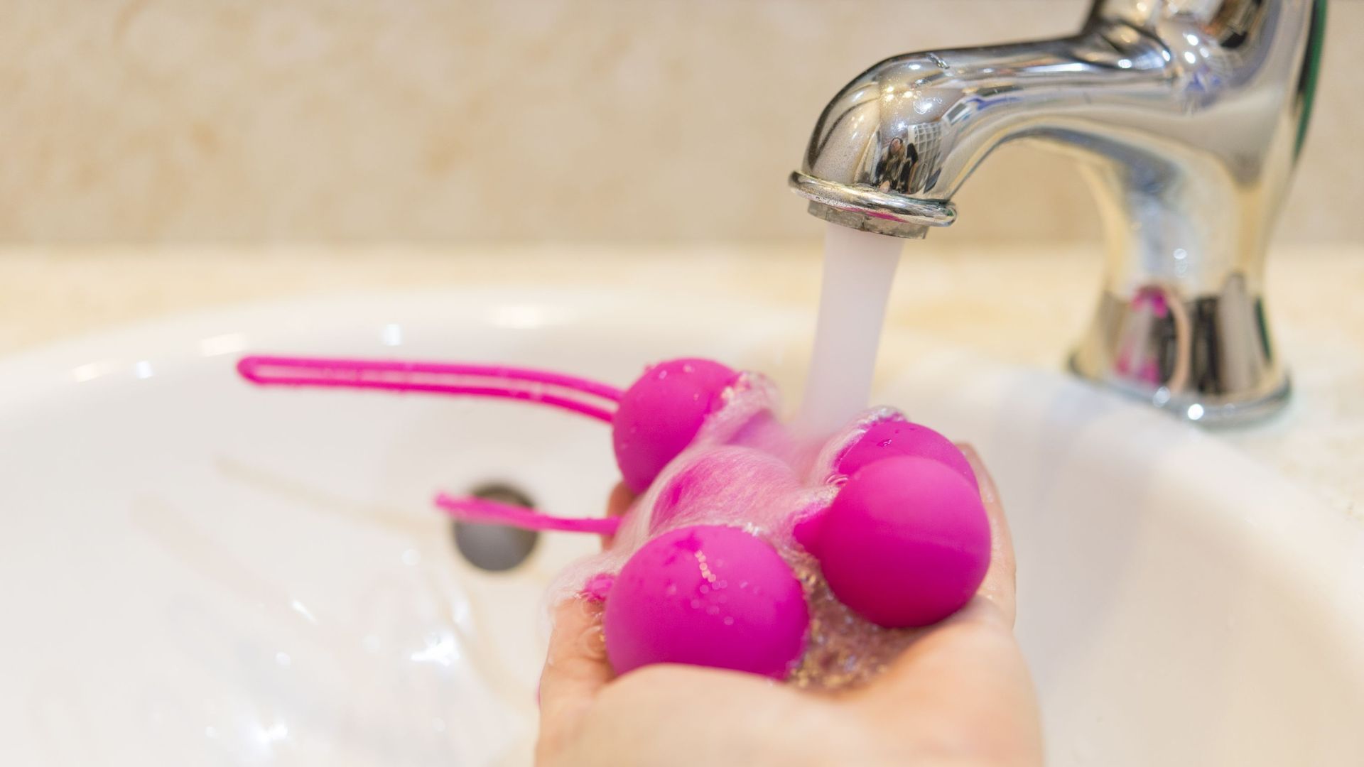 Cropped Hand Cleaning Sex Toys In Sink