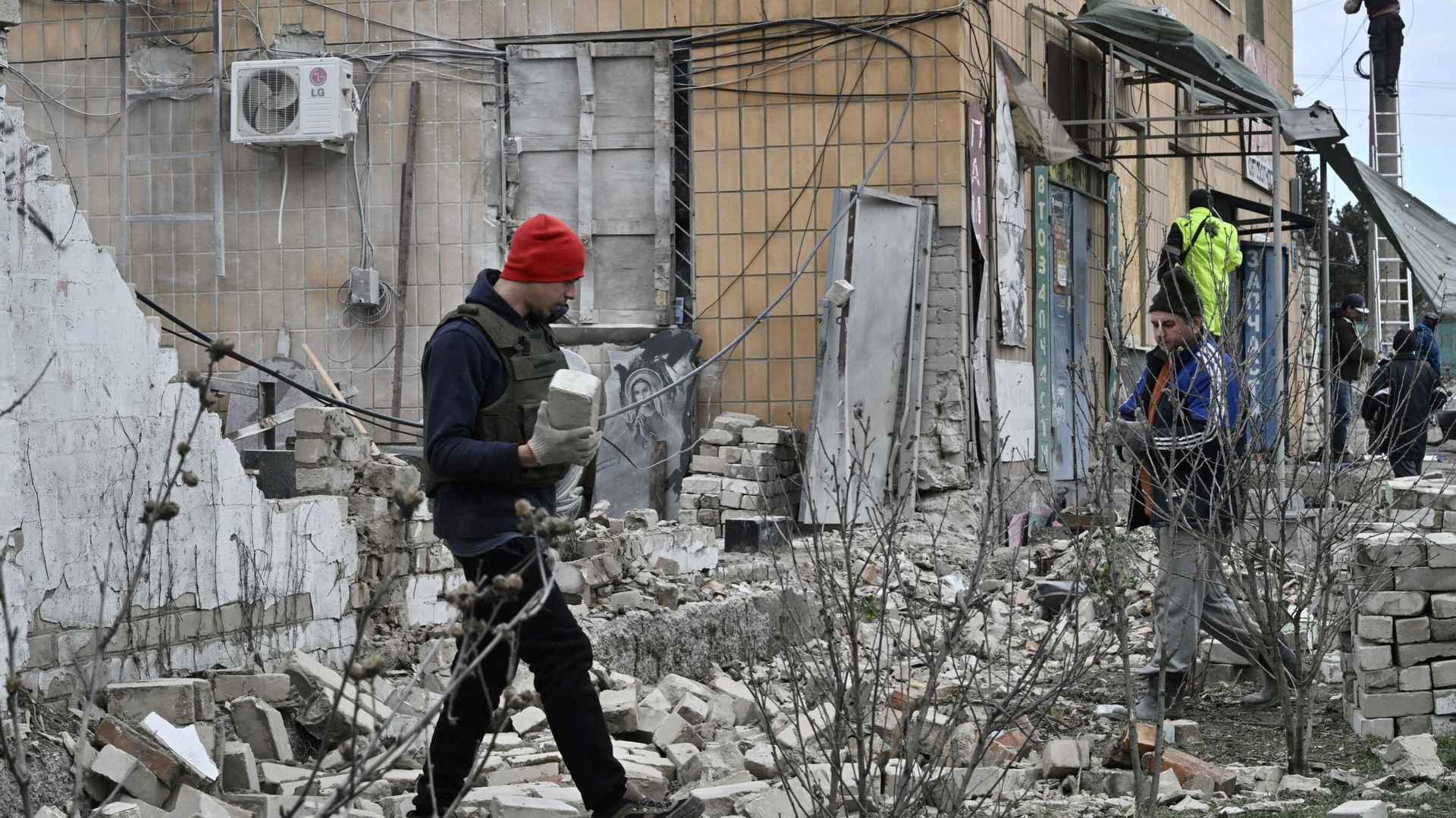 Des personnes dégagent des débris à côté d'un magasin endommagé à la suite d'une attaque à Kherson, le 4 février 2023, dans le cadre de l'invasion russe de l'Ukraine.