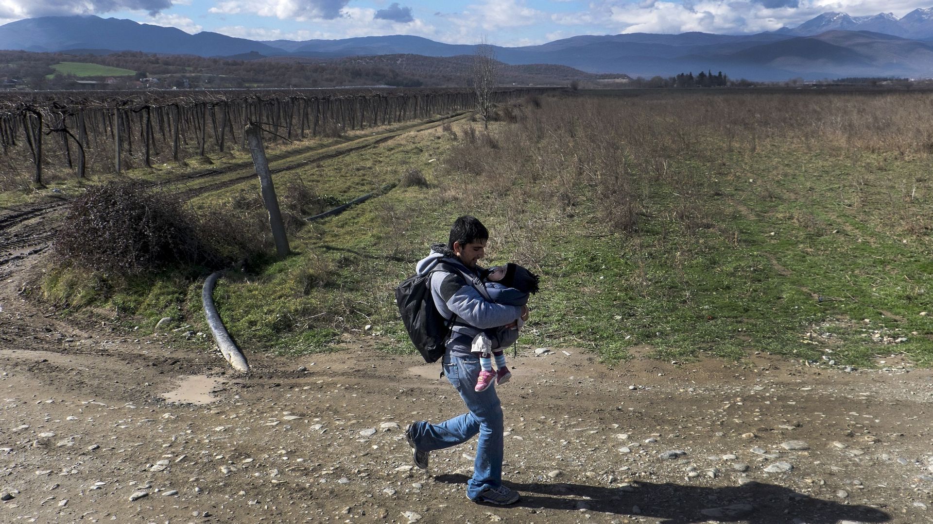 Un homme transportant un jeune enfant traverse la frontière greco-macédonienne le 14 février dernier. 