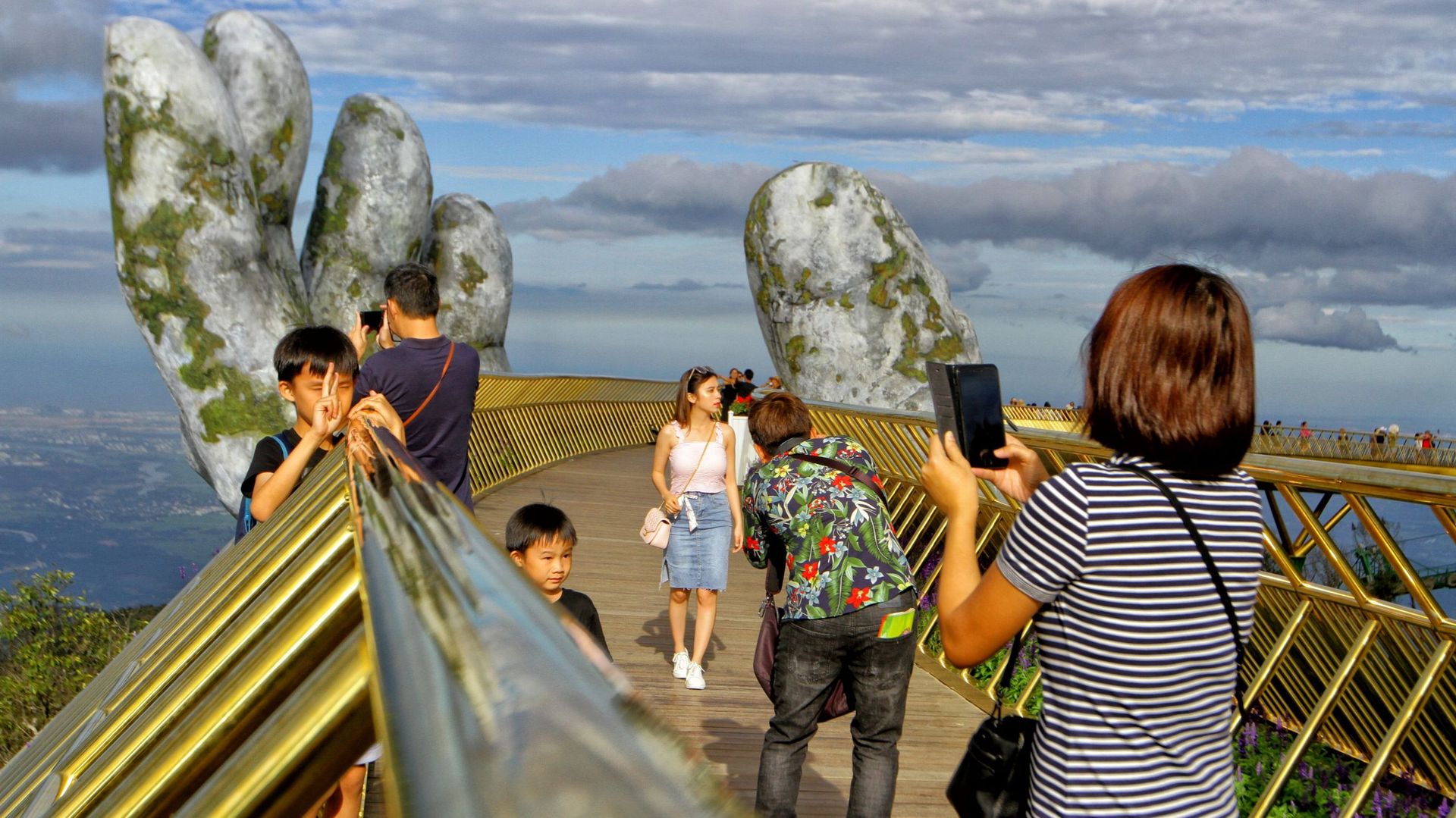 Des touristes posent sur le Cau Vang "Golden Bridge" des les collines Ba Na près de Danang 