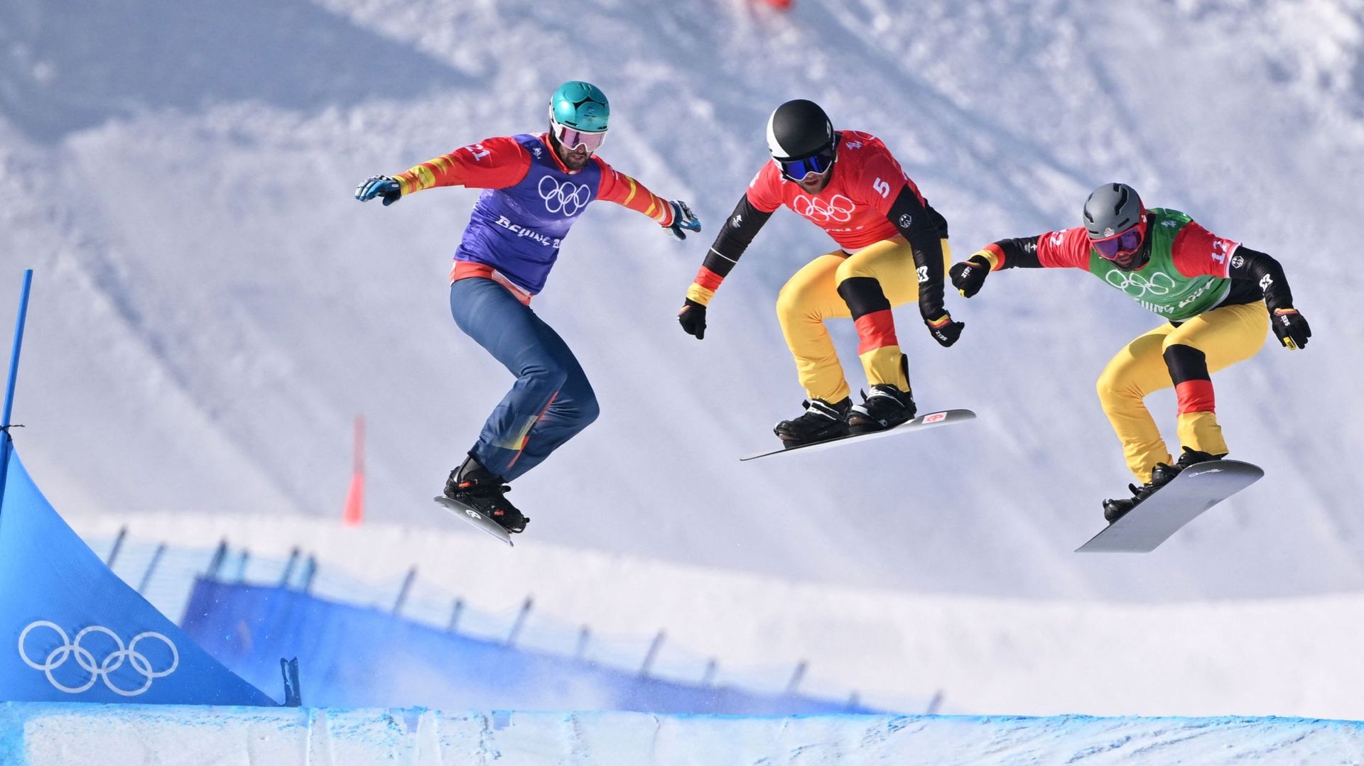 Le snowboardeur espagnol Lucas Eguibar, à gauche, a la lutte avec d’autres concurrents lors de son 1/8e de finale en snowboardcross aux Jeux olympiques de Pékin.