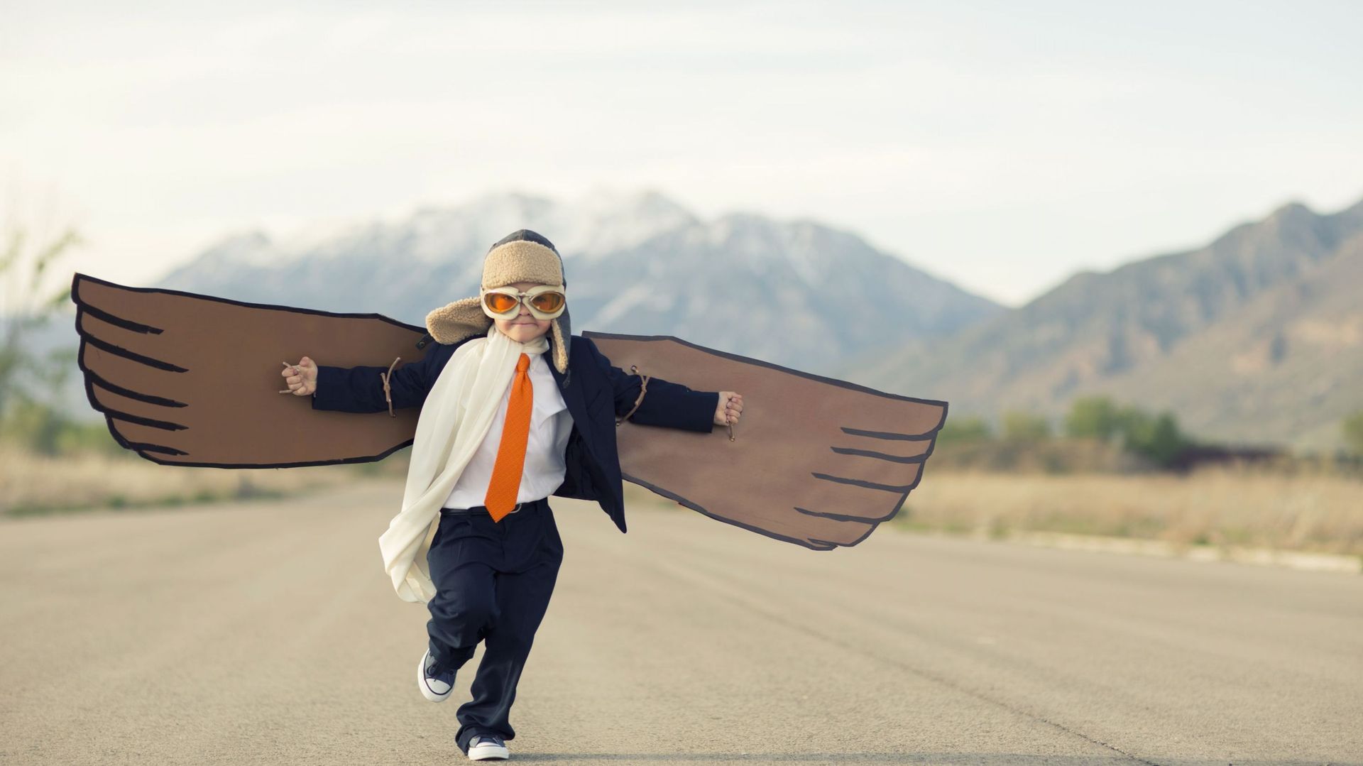 Young Boy Businessman Dressed in Suit with Cardboard Wings