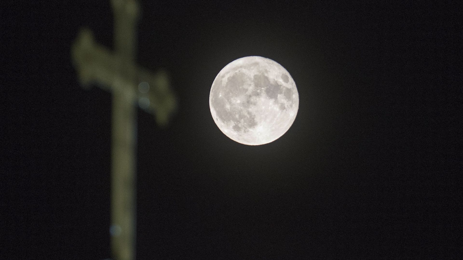 Une pleine lune, la "superlune des fraises", se lève au-dessus d'une croix sur l'église Saint-Jean-Baptiste à Skopje, le 14 juin 2022.