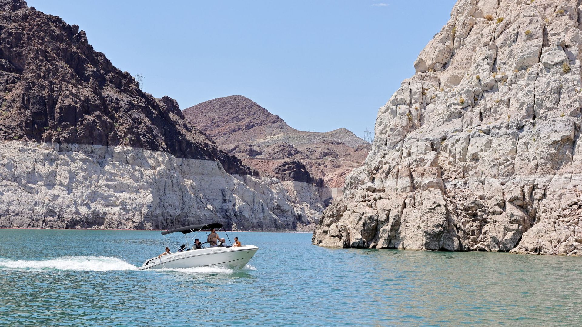 Un bateau navigue devant des rochers tachés de minéraux dans The Narrows, en amont du barrage Hoover, le 28 juillet 2022, dans la zone de loisirs nationale du lac Mead, dans le Nevada.