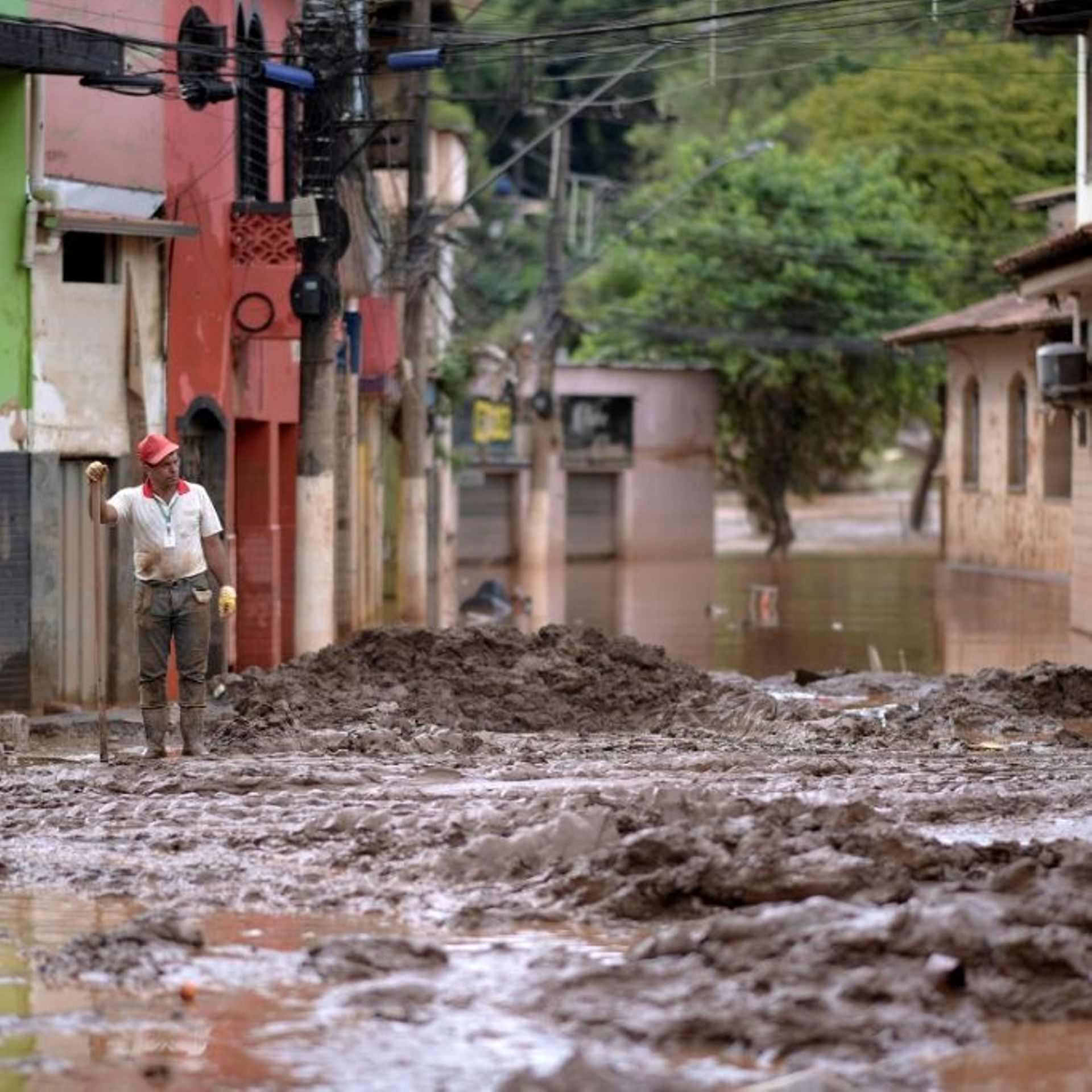 Un homme tente de nettoyer une rue après les inondations à Raposos, dans le sud-est du Brésil, le 11 janvier 2022
