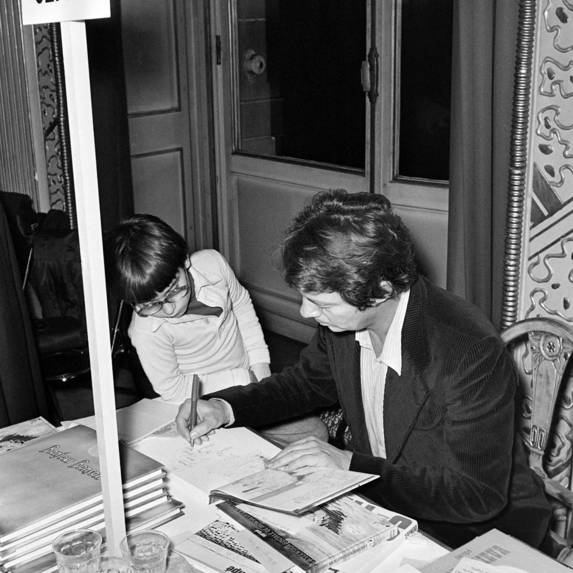 Le dessinateur français Jean-Jacques Sempé, généralement connu sous le nom de Sempé, dédicace un livre à un enfant le 6 décembre 1975.