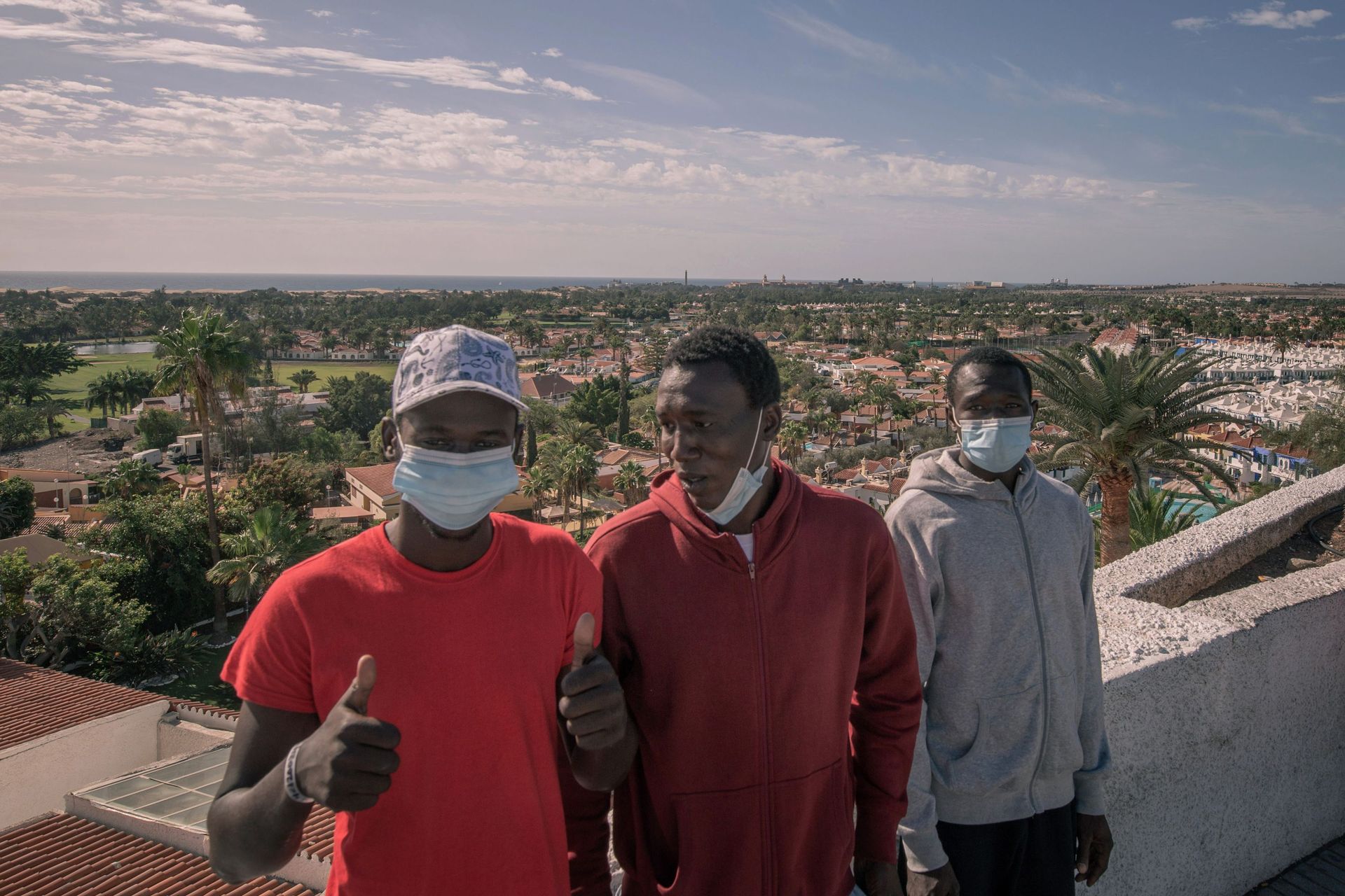 Trois migrants maliens se tiennent devant l'hôtel où ils seront hébergés après leur arrivée en bateau sur l'île canarienne de Gran Canaria le 23 novembre 2020.