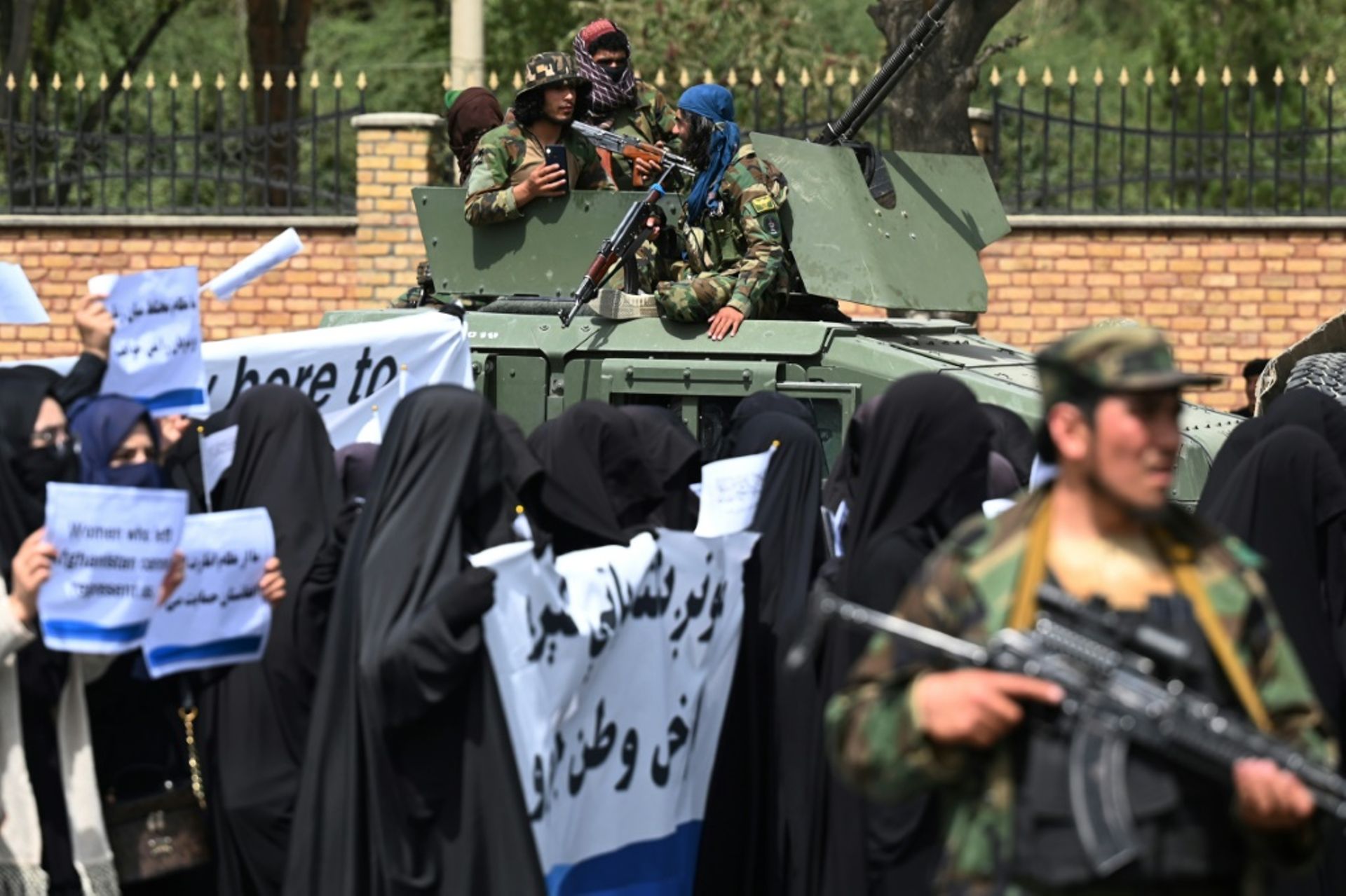 Des combattants talibans encadrent une marche d’Afghanes en niqabs noirs lors d’un rassemblement devant l’Université Shaheed Rabbani, le 11 septembre 2021 à Kaboul
