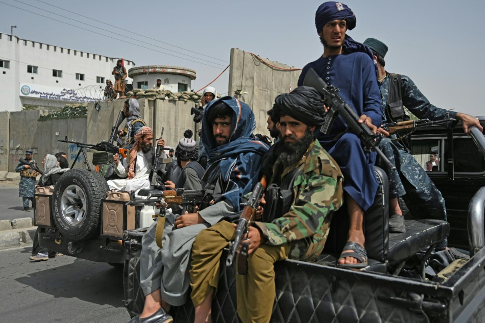 Des combattants talibans armés escortent des Afghanes en niqabs noirs lors d’un rassemblement pro-talibans devant l’Université Shaheed Rabbani, le 11 septembre 2021 à Kaboul