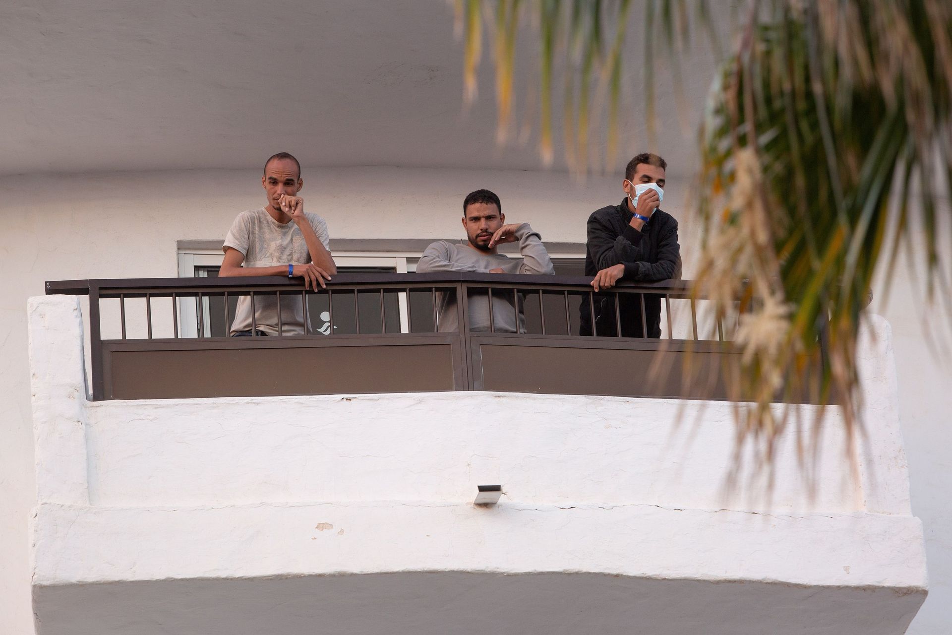 Des hommes se tiennent sur un balcon dans l'un des complexes touristiques abritant quelque 5500 migrants à Playa del Ingles, sur l'île espagnole de Grande Canarie, le 22 novembre 2020.