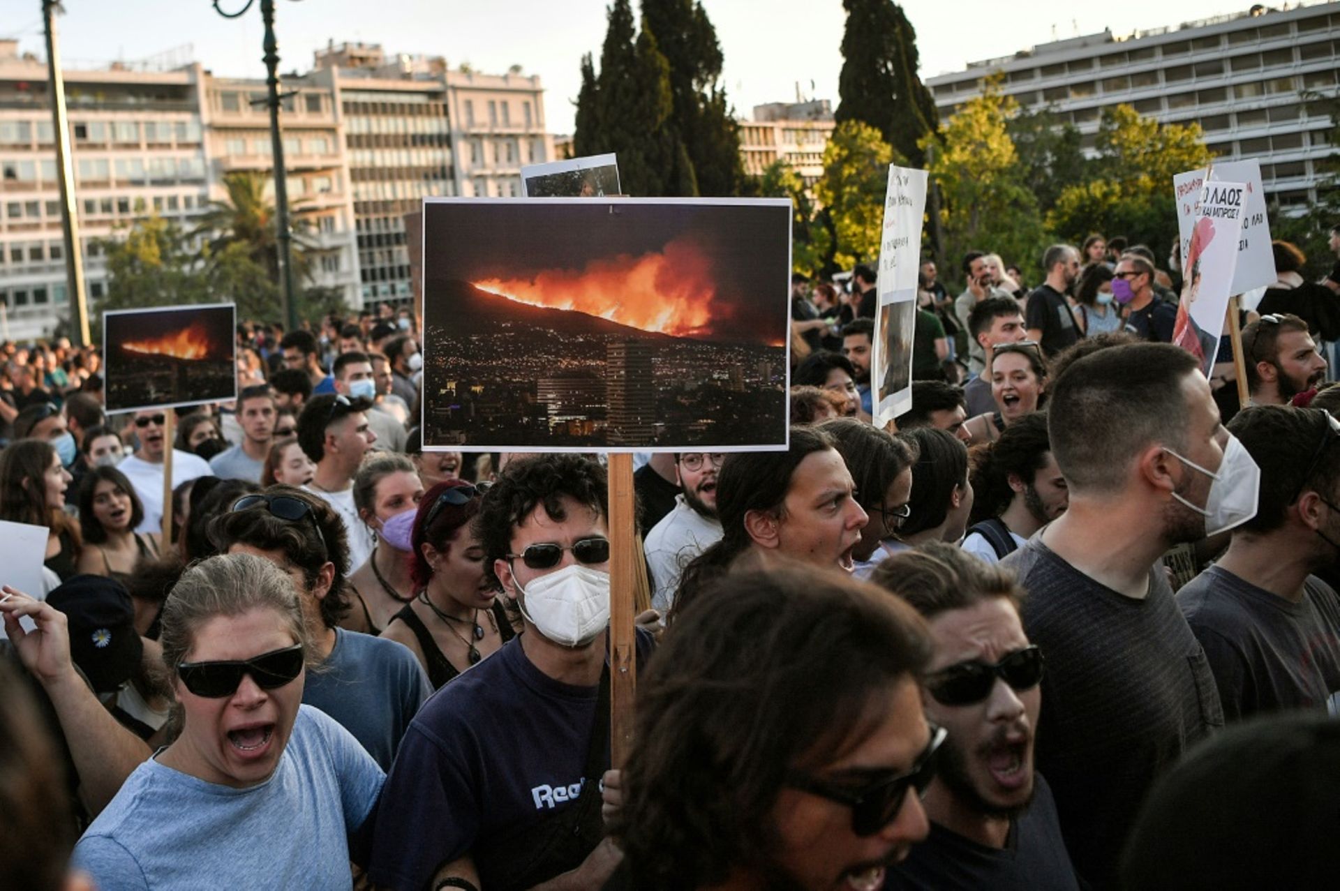 Des manifestants brandissent des photos des feux de forêts pour protester contre la nouvelle loi environnementale en discussion au parlement à Athènes le 28 juillet 2022.