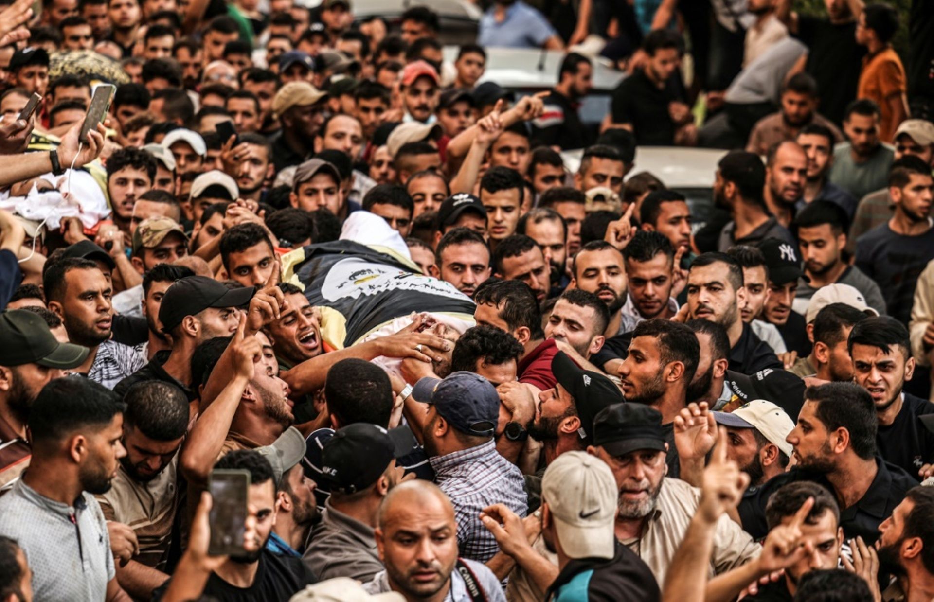 Des Palestiniens portent le corps de deux victimes des frappes israéliennes à Gaza, le 5 août 2022