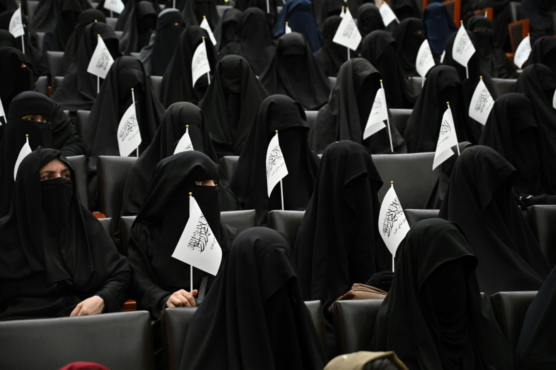 Des étudiantes afghanes en niqabs noirs, un drapeau taliban à la main, écoutent un discours lors d’un rassemblement pro-talibans à l’université Shaheed Rabbani, le 11 septembre 2021 à Kaboul