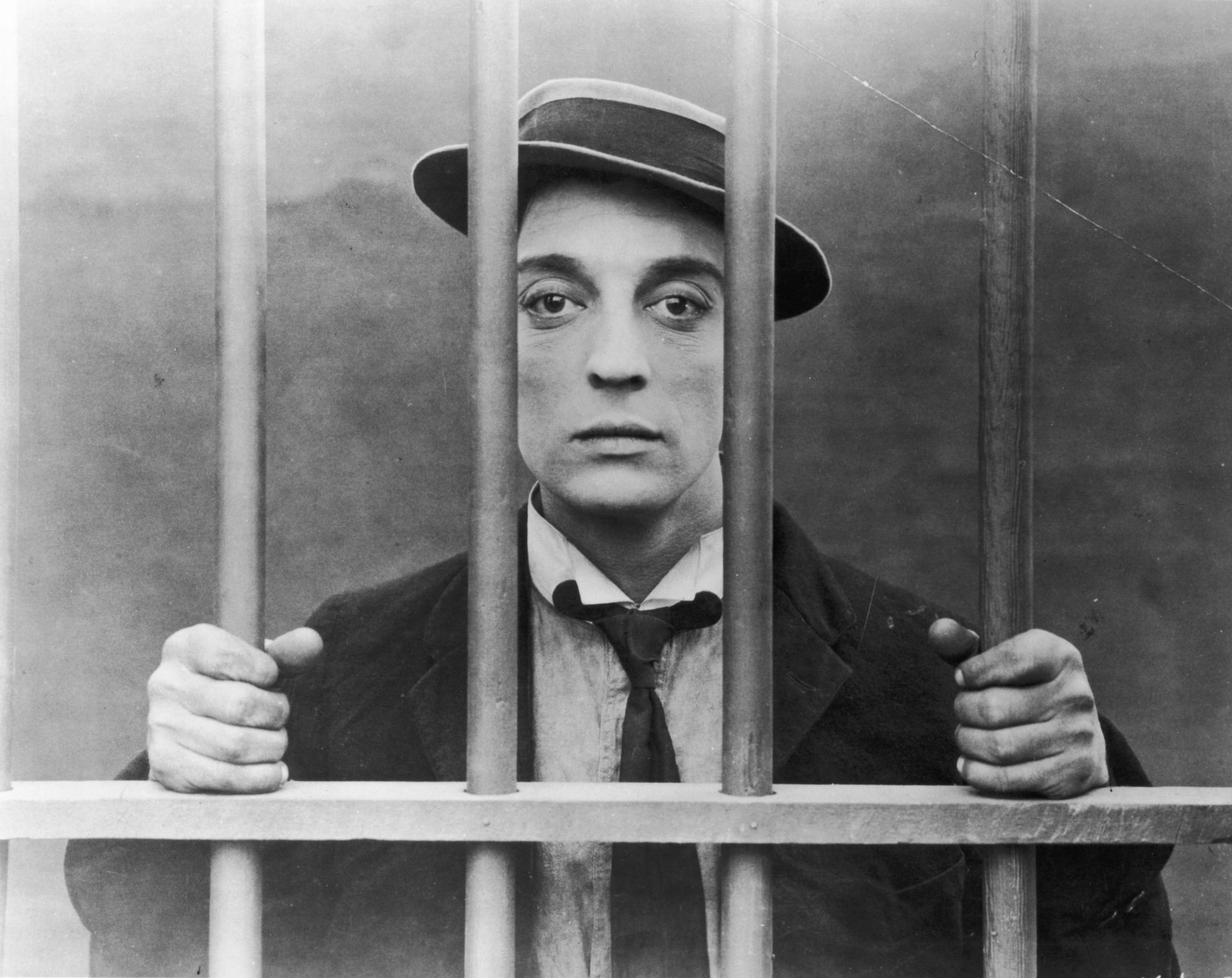 American comedic film star Buster Keaton grasps prison bars in a promotional portrait for his silent film, 'The Goat'. 