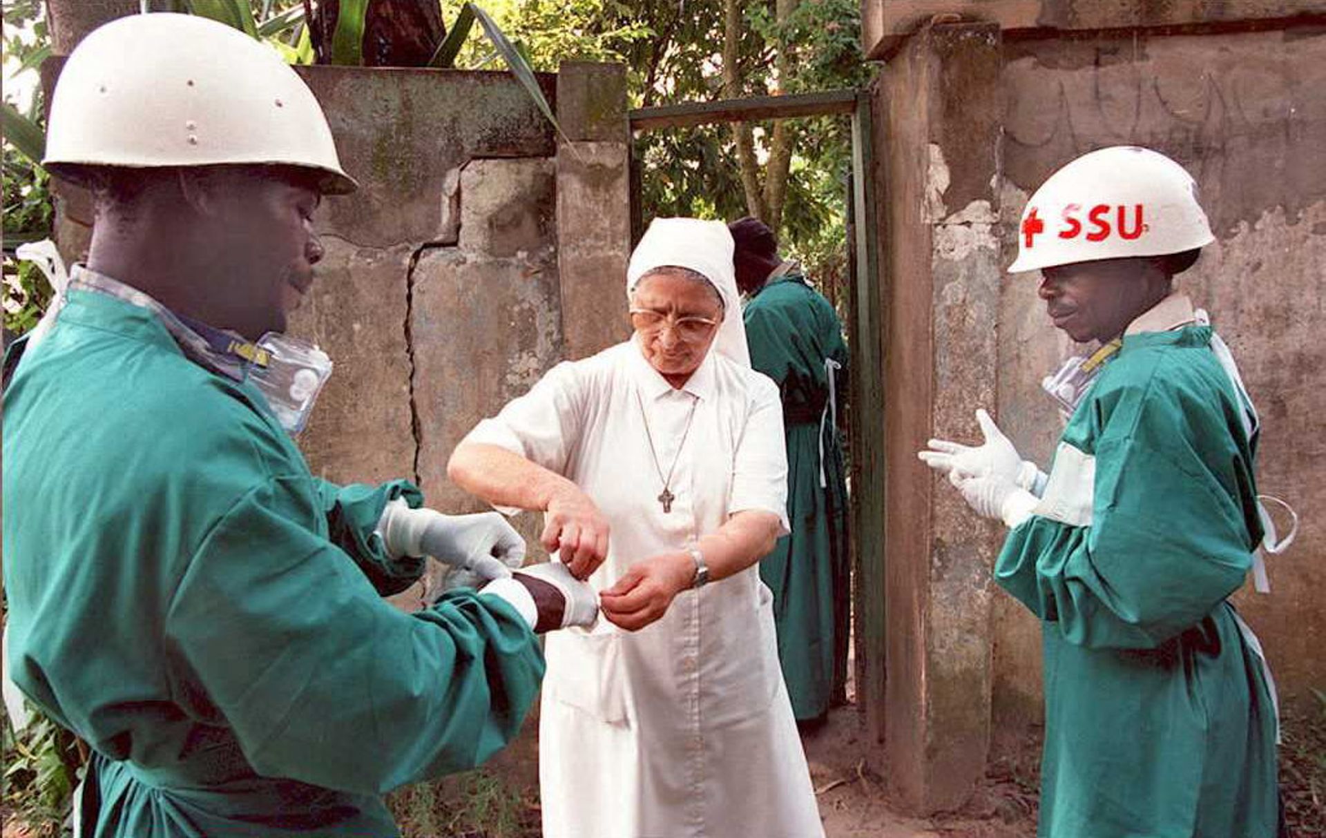 Une religieuse italienne (au centre) aide deux agents de santé zaïrois à retirer leurs gants chirurgicaux  dans un hôpital de Kikwit, la zone au centre de l'épidémie mortelle du virus Ebola dans les années 1990. 