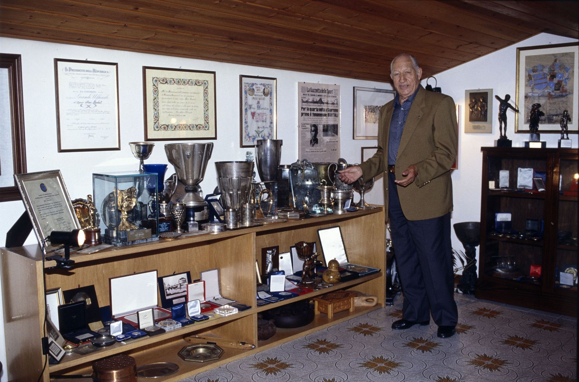 Gino chez lui, présentant ses nombreuses récompenses de champion cycliste en 1994…