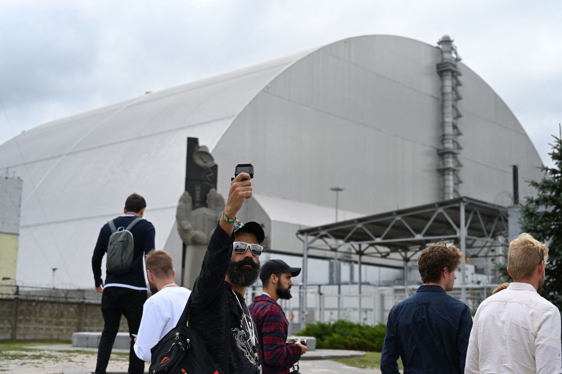 Des touristes devant le nouveau dôme métallique entourant le réacteur détruit, à l'usine de Tchernobyl, en Ukraine en 2019.La série à succès "Tchernobyl" a amené une nouvelle génération de touristes dans la zone de la catastrophe nucléaire, mais les guide