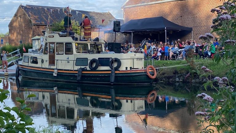 Guinguette itinérante : trois musiciens dans un bateau et le public au bord de l’eau