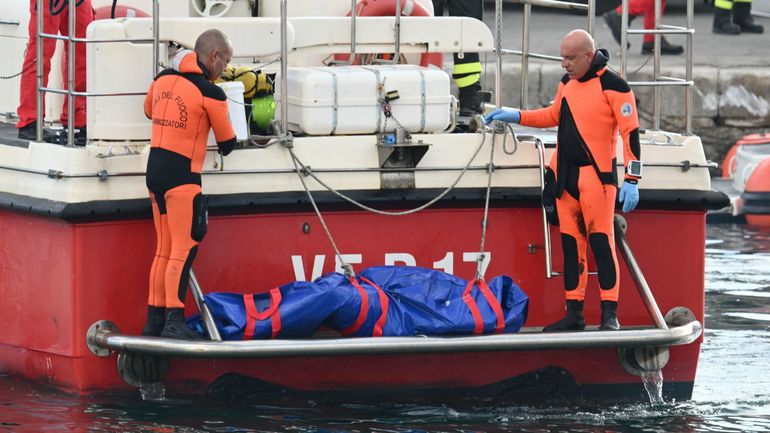 Des plongeurs du Vigili del Fuoco, le corps italien des pompiers, arrivent dans le port de Porticello, près de Palerme, avec un sac mortuaire à l'arrière du bateau, le 22 août 2024, trois jours après le naufrage du Bayesian, un yacht de luxe battant pavil